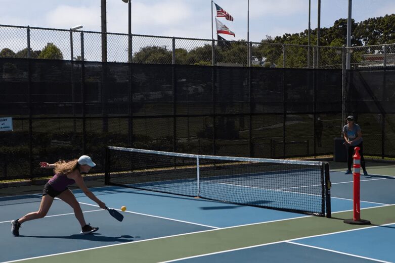 In the court, a pickleball player plays singles pickleball using a pickleball and pad