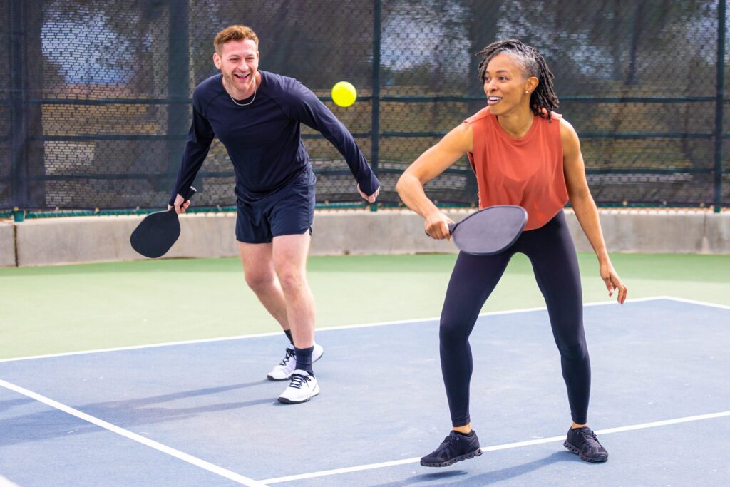 This image shows men and women playing pickleball together 